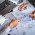 Construction engineering or architect discuss a blueprint while checking information on drawing and sketching, meeting for architectural project of partner.